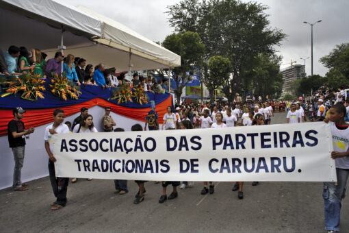 Foto com faixa da Associação de Parteiras Tradicionais de Caruaru em destaque e várias parteiras seguindo