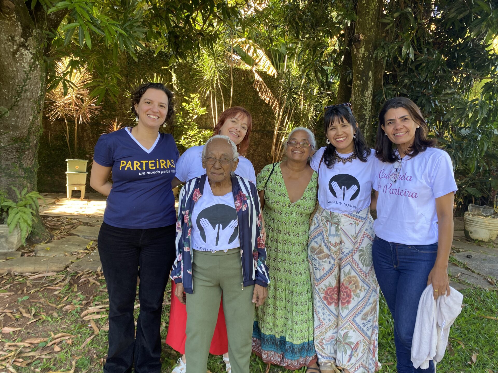 Fotografia de Socorro da Silva. Na imagem, Dona Prazeres na frente, atrás, da esquerda para a direita: Júlia Morim, Elaine Müller,
Conceição Nepomuceno, Marília Nepomuceno e Vânia Maria. Equipe Museu da Parteira em Brasília-DF.